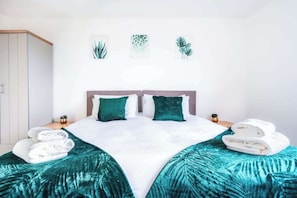 Un lit avec deux oreillers, une couvre-lit turquoise et une couverture blanche.