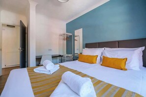 A hotel room with a bed, a desk, a chair, and a mirror.