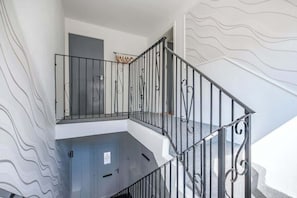 A staircase with a metal railing, a door at the bottom, and a wall with a wavy pattern.