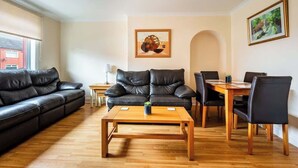 Una sala de estar con sofá, mesa de centro, mesa de comedor, sillas y obras de arte en las paredes.