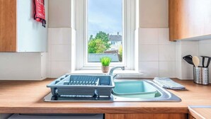 A kitchen with a window, a sink, a dish rack, and a plant. - Millfield House -2 Bed in Motherwell near Motorway (North Lanarkshire)