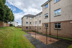 Stylish residential building with a flat roof and brick exterior, featuring multiple windows and a grassy lawn.