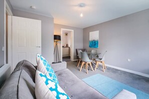 Relax in this stylish living room with a sofa and dining area, featuring a glass table and comfortable seating.