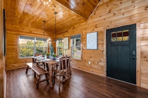 A wooden cabin interior with a dining table, benches, and chairs.