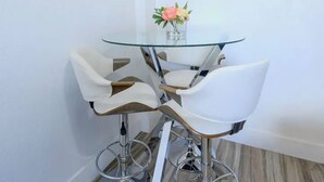 A small glass-top table with two white chairs and a vase with flowers. - Stylish Miami Apartment 9 Minutes from the Airport (Miami)