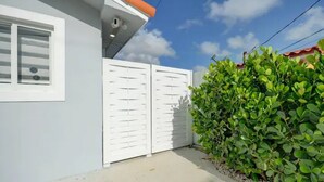 A residential building with a white exterior, a red roof, and a white gate. - Stylish Miami Apartment 9 Minutes from the Airport (Miami)