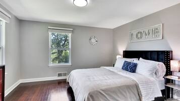 Une chambre à coucher avec un lit, une table de chevet, une horloge murale et une fenêtre.