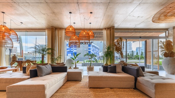 A modern living room with a sectional sofa, large windows, and hanging wicker lamps. - Ambar Hotel (Punta del Este)