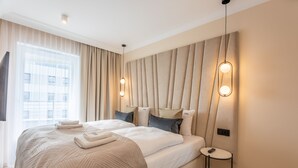 Ett modernt hotellrum med en stor säng, ett nattduksbord och utsikt över staden genom fönstret.