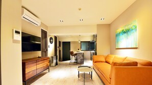 Un soggiorno moderno con divano, tavolino e televisione. Si nota una zona cucina sullo sfondo.