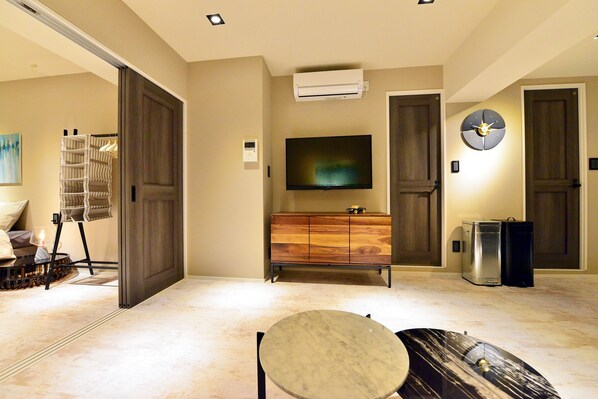 A modern living room with a flat-screen TV, wooden cabinet, and a marble coffee table. - Omotesando Chic 2-bedroom (Minato)