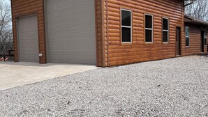 A log cabin with a garage and a covered outdoor area. - Eureka Springs, AR. Cozy log cabin studio, sleeps 2-4.Lake view- 15 min to town  (Eureka Springs)
