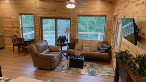 A cozy log cabin interior with a leather sofa, a dining area, and a fireplace. - Eureka Springs, AR. Cozy log cabin studio, sleeps 2-4.Lake view- 15 min to town  (Eureka Springs)