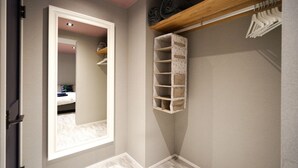 Ein Schlafzimmer mit einem großen Spiegel, einem Holzregal über dem Bett und einer eingebauten Stauraum-Einheit mit mehreren Fächern.