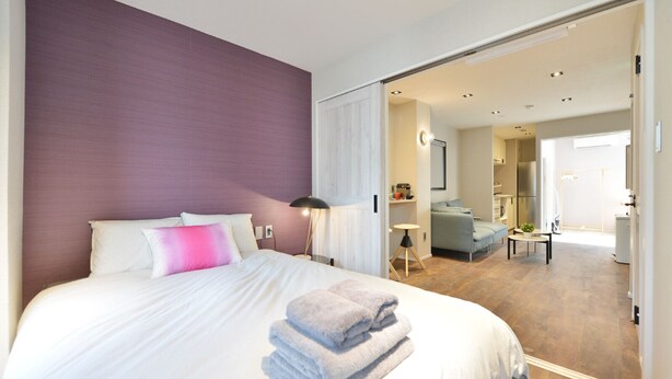 Una habitación de hotel moderna con una cama grande, un escritorio y un sofá en la zona de estar contigua.