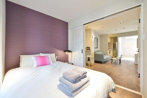 Et moderne hotelværelse med en stor seng, et skrivebord og en sofa i det tilstødende opholdsområde.
