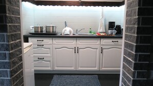 Een keuken met witte kastjes, een zwart aanrecht en een blauw tapijt.