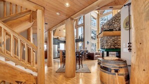 Un interior espacioso con una escalera de madera, una chimenea de piedra y un barril rústico.