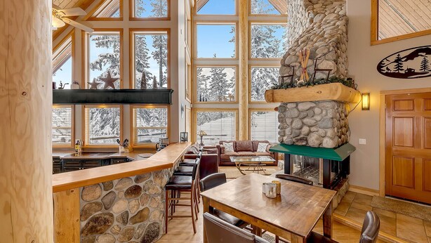 Una cocina amplia con ventanas grandes, una chimenea de piedra y un comedor de madera.