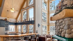 Una cocina amplia con chimenea de piedra, ventanas grandes y techo alto.