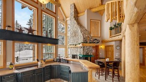 Una cocina amplia con armarios oscuros, ventanas grandes y una chimenea de piedra.