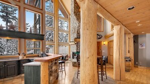 Una cocina amplia con ventanas grandes, una chimenea de piedra y vigas de madera.