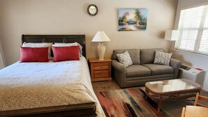 Une chambre à coucher avec un lit, une table de chevet, une lampe et un canapé.