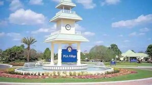 Un belvédère agrémenté d’une horloge, entouré d’une fontaine circulaire et d’un panneau indiquant « PGA Village ».