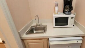 A compact kitchenette with a sink, microwave, and coffee maker.