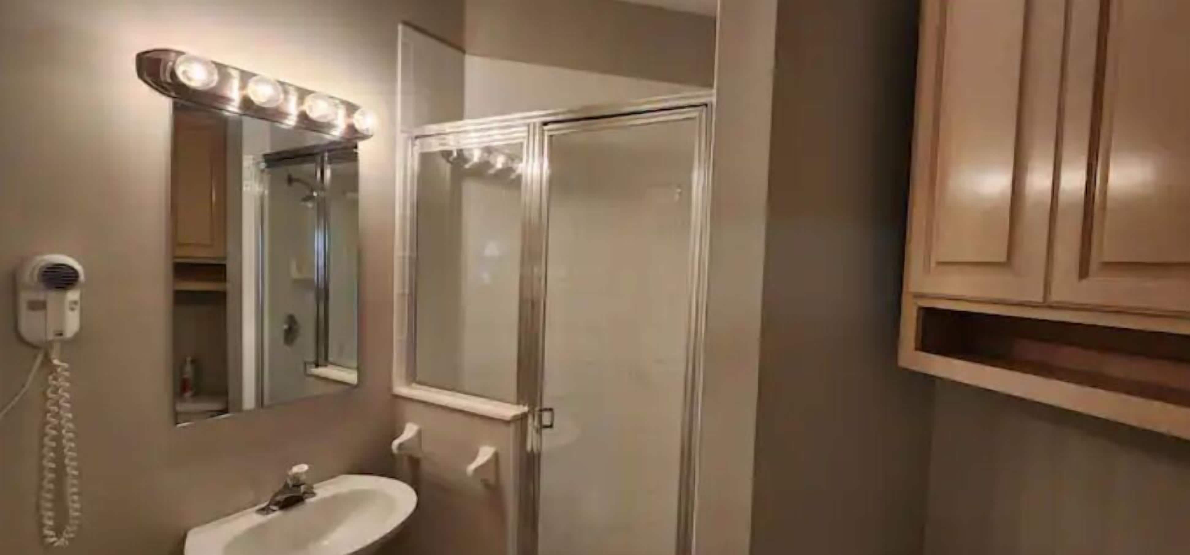 Un baño con lavamanos, espejo y ducha.