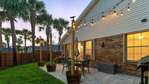 A patio with outdoor furniture, a pergola with string lights, and a brick wall. - Walk to the Beach | Community Pool & Private Fenced Yard (Miramar Beach)