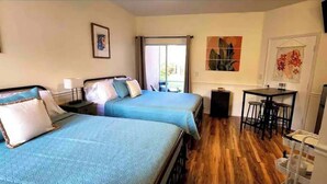 Una habitación con dos camas, una mesita y una silla.