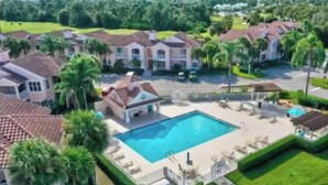 Zona residencial con piscina rodeada de césped cuidado y palmeras.