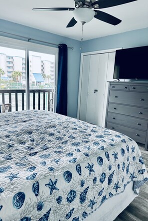 A bedroom with a bed, a ceiling fan, a dresser, and a TV.
