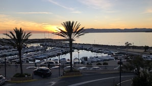 A marina with boats docked, a parking area, and a sunset in the background. - Superb new designer house with panoramic sea views (Saint-Cyr-sur-Mer)