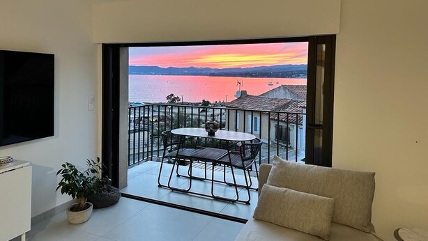 A balcony with a table and chairs, a sofa, and a TV. - Superb new designer house with panoramic sea views (Saint-Cyr-sur-Mer)