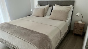 A neatly made bed with a grey headboard and a bedside table with a lamp. - Superb new designer house with panoramic sea views (Saint-Cyr-sur-Mer)