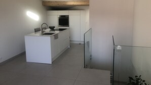 A modern kitchen with white cabinetry, a built-in oven, and a stainless steel sink. - Superb new designer house with panoramic sea views (Saint-Cyr-sur-Mer)