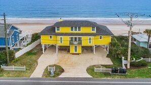 A two-story yellow building with a balcony, located near a beach with a clear view of the ocean. - Once Upon a Tide Home with Hot Tub & Fire Pit (Ponte Vedra Beach)