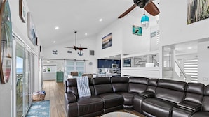 A spacious living area with a large leather sectional sofa, a round coffee table, and a ceiling fan. - Once Upon a Tide Home with Hot Tub & Fire Pit (Ponte Vedra Beach)
