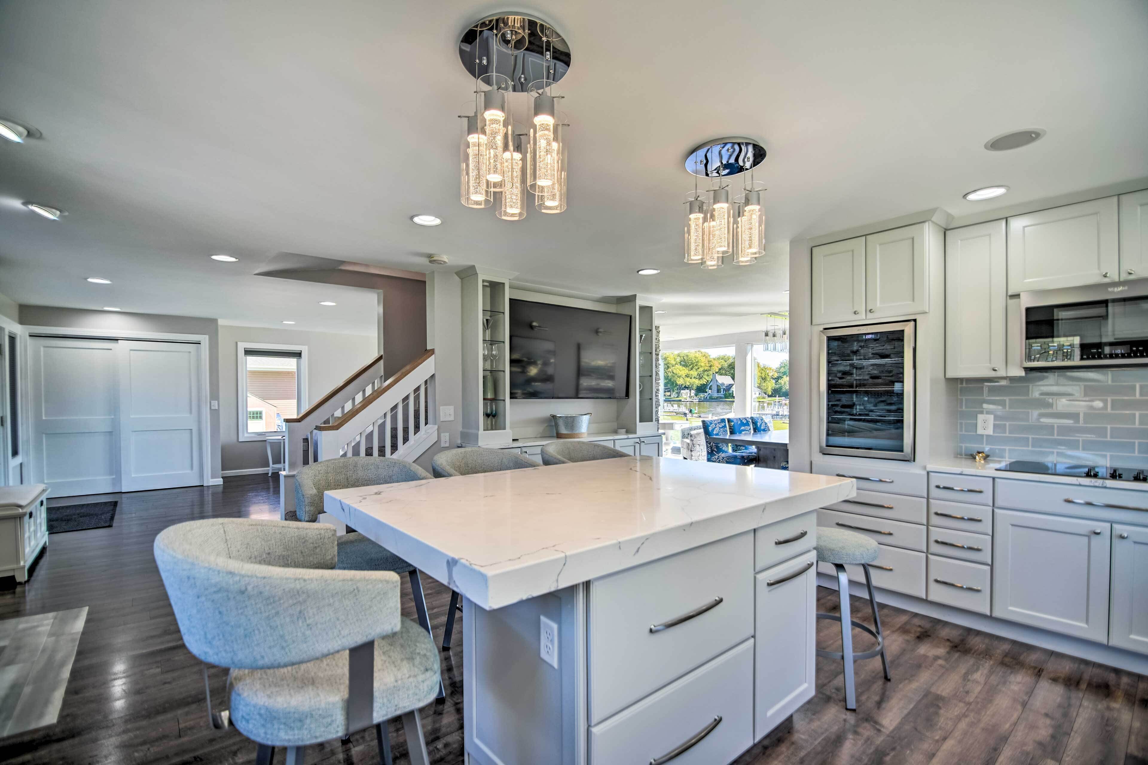 A modern kitchen with a central island, white cabinetry, and pendant lighting.