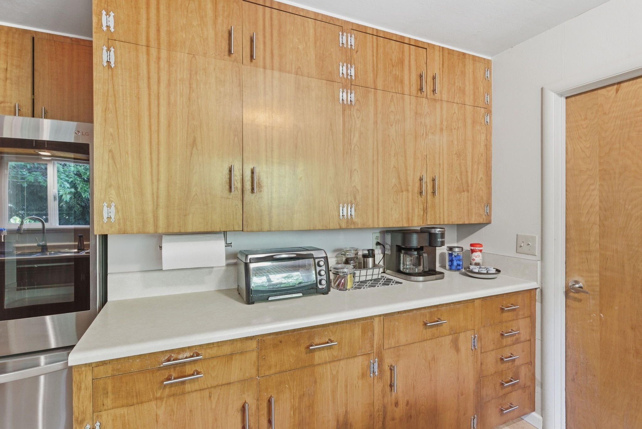 A kitchen with wooden cabinets, a toaster, a coffee maker, and a stainless steel oven.
