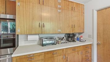 A kitchen with wooden cabinets, a toaster, a coffee maker, and a stainless steel oven.