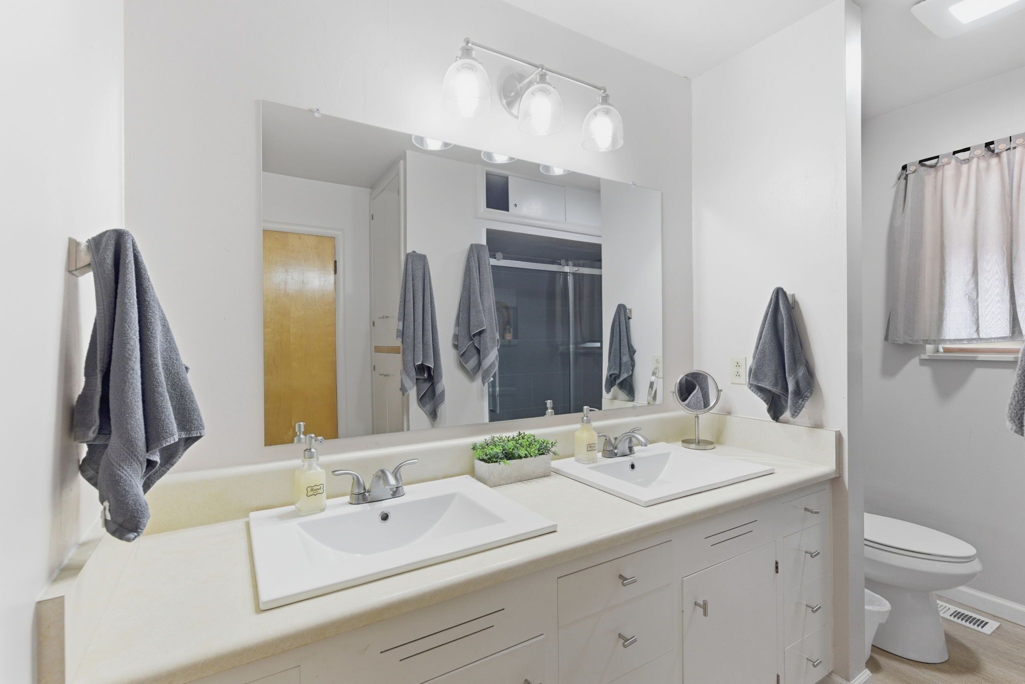 Une salle de bain moderne avec deux lavabos, un grand miroir et un espace douche.