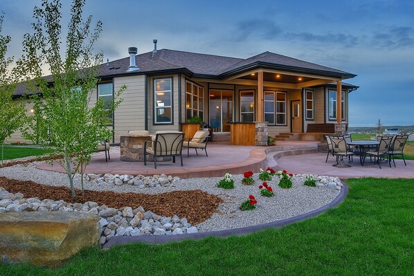 A modern house with a patio, outdoor seating, and a landscaped garden. - Hot Tub + 1,600 sq ft Golf-Course Patio • Game Room & Luxury Living (Billings)