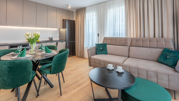 A modern living room with a sofa, a dining table with chairs, and a kitchen area with a refrigerator. - Vacation apartment by the sea, vacation on the island of Usedom, Apartment SUN TOWERS B107 (Swinoujscie)