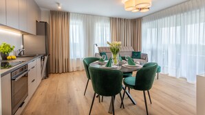 A modern kitchen with a dining area. There is a dining table with chairs, a chandelier, and a large window with curtains. - Vacation apartment by the sea, vacation on the island of Usedom, Apartment SUN TOWERS B107 (Swinoujscie)