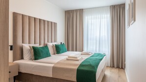 A hotel room with a large bed, a bedside table, a lamp, and a window with curtains. - Vacation apartment by the sea, vacation on the island of Usedom, Apartment SUN TOWERS B107 (Swinoujscie)