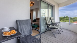 A balcony with a table set with croissants and a cup, a sofa, and striped chairs. - Vacation apartment by the sea, vacation on the island of Usedom, Apartment SUN TOWERS B107 (Swinoujscie)