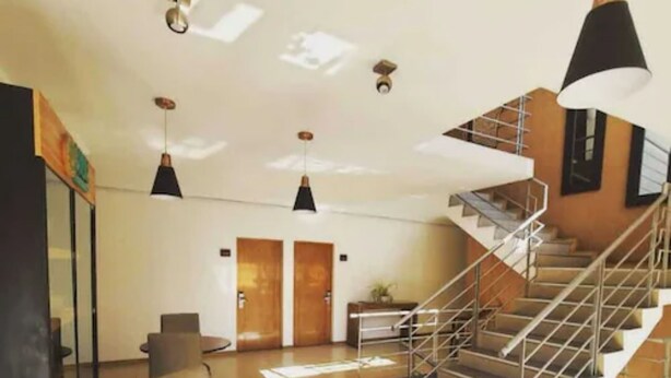 A modern interior with a staircase, a round wooden table, and two doors. - Hotel Capelli Express (Talca)